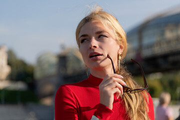 Fashionable woman in red dress enjoys city stroll under bright sunlight