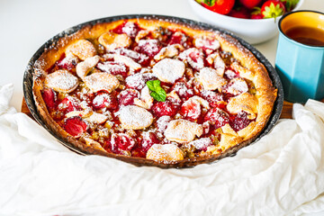 Rhubarb tart with strawberries and sugar on a white table. Traditional French dessert. Top view.