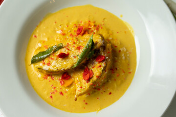 Delicious Fish Curry in Yellow Sauce Garnished with Herbs and Spices