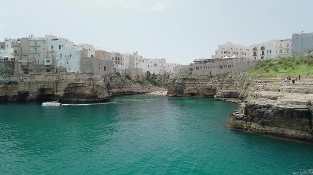 Drone footage of Polignano a Mare, Italy with Lama Monachile beach, turquoise sea, dramatic cliffs, and scenic views of the Adriatic coastline in Puglia.