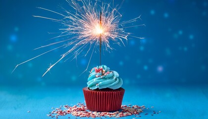 blue cupcake with red and white sprinkles and lit sparkler on a blue background