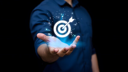 Achieving Goals A Person's Hand Holding a Digital Target with Arrow Hitting the Center Surrounded by Glowing Particles on a Dark Background Symbolizing Success and Precision in Business Strategy