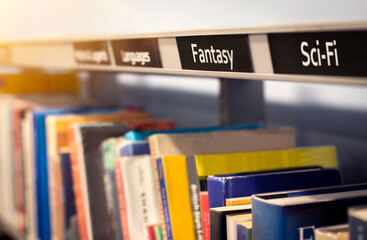 Sci-fi and fantasy bestseller fiction books - novels on bookshelf under genre categories. Reading...