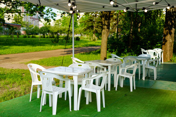 Outdoor cafe setting with white tables and chairs under a canopy