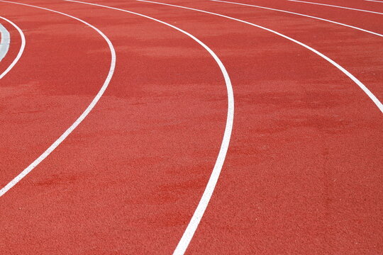 Red artificial running track with white round dividing lines, treadmill rubber texture, sports, athletics