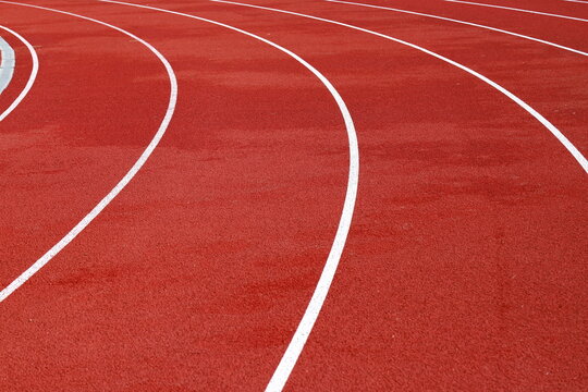 Red artificial running track with white round dividing lines, treadmill rubber texture, sports, athletics