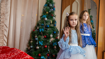 Little girls in festive dress dancing near christmas tree at home