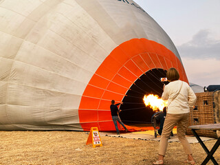 woman taking a photo of filling hot air balloon with fire