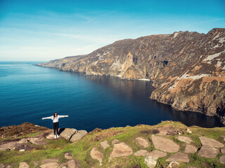 Teenager girl sightseeing stunning Slieve League cliff nature scenery and Atlantic ocean. Blue...