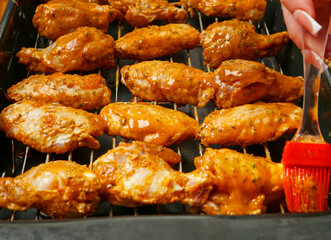 Cooking fresh chicken wings on an oven. The product is covered in red Asian style sauce and ready for cooking in high temperature. Party finger snack food.