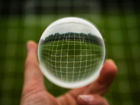 Football or soccer goal post net in glass ball which is hold by a man. Forecasting sport results in popular world sport. Betting on club and national teams concept. - Powered by Adobe