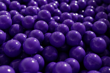 A large group of glossy purple plastic balls tightly packed together. Shot from top in soft light. Concepts: childhood, play, fun, color. Perfect for themes of entertainment and abstraction.