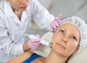 Woman getting facial radio wave lifting skin tightening procedure in beauty salon. RF-lifting...