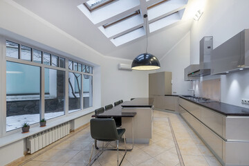 Modern kitchen interior design with panoramic window. Windows in the roof. Light grey furniture...