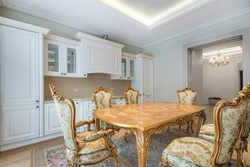The refined interior of a luxurious dining room kitchen in a classic style. White kitchen set,...