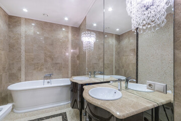 Exquisite bathroom interior design with beautiful lamps on the mirrored wall. Elegant cabinets with...