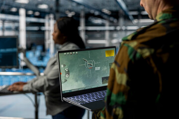 Close up of military officer in data center looking at missile lock interface displayed on laptop...