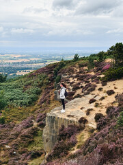 Woman standing at the edge of the mountain, heather season at North York Moors National Park, England, UK