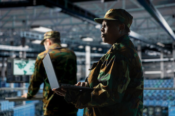 Soldier in server hub updating secure firmware on military data center hardware. African american...