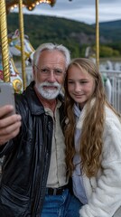 Obraz premium A grandparent and grandchild happily take a selfie together on a carousel merry-go-round, surrounded by vibrant colors and joyful atmosphere. The moment captures their bond and excitement