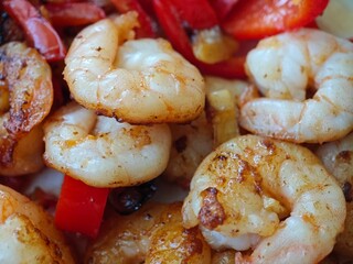 Juicy shrimp sautéed with colorful bell peppers and spices at a vibrant kitchen setting in the...