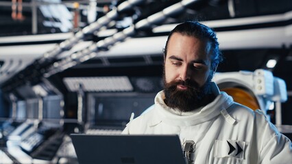 Astronaut checking human expansion in space mission data on laptop during cosmic journey. Orbit station crew managing systems using notebook during mankind survival expedition © DC Studio