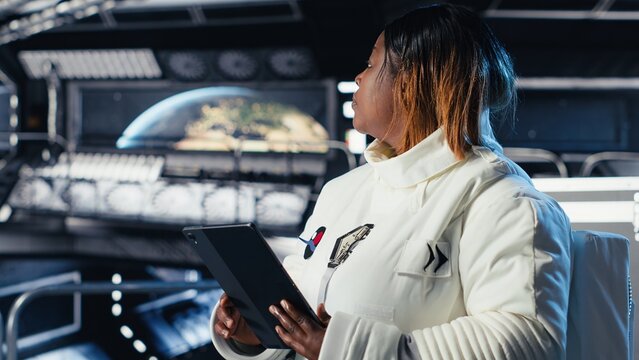 Female astronaut using tablet to check space station analytics after completing surface mission on unfamiliar planet. Woman inputting navigation coordinates, preparing for return to Earth - Powered by Adobe