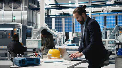 Facility supervisor in a suit monitoring solar panel assembly line, reflecting professional...