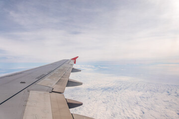 View from the airplane window at a beautiful cloudy sky and the airplane wing