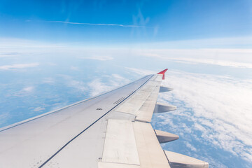 Obraz premium View from the airplane window at a beautiful cloudy sky and the airplane wing