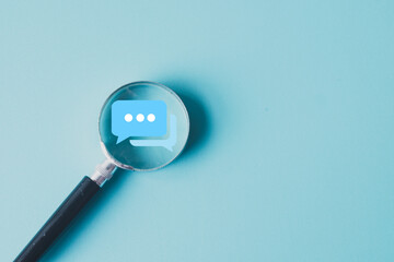 Magnifying glass focusing on a chat bubble icon. Concept for analyzing online communication, social...