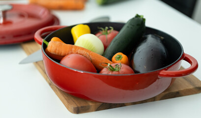 red beautiful cast iron skillet and fresh vegetables. cooking vegetable stew in cast iron. fresh...