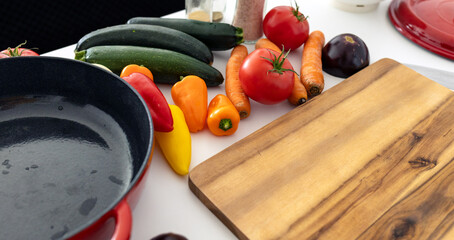 red beautiful cast iron skillet and fresh vegetables. cooking vegetable stew in cast iron. fresh...