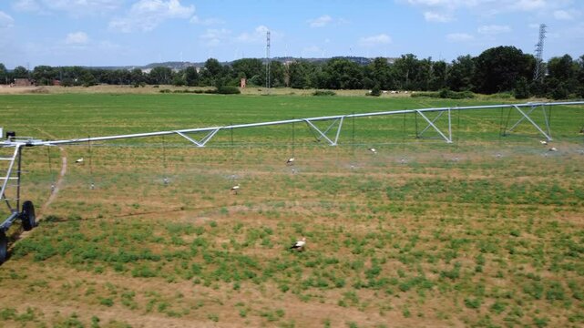 Irrigation Pivot in Action: Serene Aerial View of a Watered Field. Lateral Pan Shot.