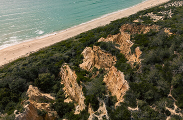 Stunning aerial photo of dramatic cliffs and lush greenery meeting a sandy beach along the Lisbon...