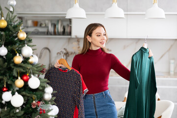 Portrait of attractive young woman selecting dress for Christmas celebration