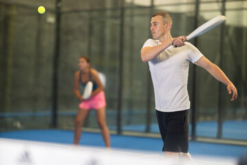 Fototapeta premium Young woman and young guy in doubles play tennis on tennis court