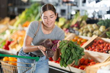 In vegetable department of bio supermarket, female customer took bunch of beetroots from window....