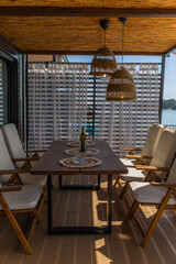 Boho style terrace on a raft, what with the glasses and white wine set up, sunny weather.