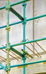 Scaffolding and rebar rods protrude from concrete at a construction site