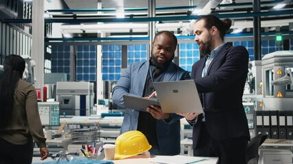 Team of diverse analysts consultants reviewing data and checklists in a high tech solar panel plant, ensuring manufacturing process meets sustainable energy and innovation standards. Camera B. - Powered by Adobe