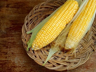Fresh corn from the harvest on a wooden plate on the table
