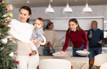 Woman decorating Christmas tree, family preparing for Christmas