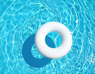 White inflatable ring floating in clear blue swimming pool creates serene and inviting atmosphere, perfect for relaxation on sunny day