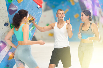 Athletic man and two women discussing climbing options near climbing wall