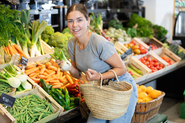 Smiling young woman customer buying fresh fennel root-crop in big grocery store