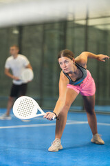 Young woman and young guy in doubles play tennis on tennis court