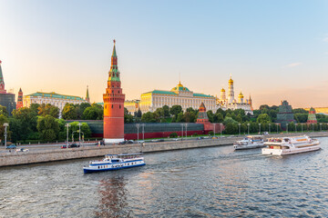 Obraz premium View of Kremlin with Vodovzvodnaya tower, Grand Kremlin Palace from repaired Bolshoy Kamenny Bridge in Moscow city on sunny summer day. Cruise ship sails on the Moscow river