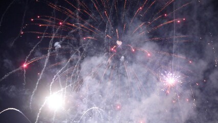 Fireworks exploding, creating colorful smoke trails in the night sky
