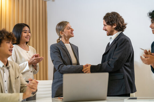 Image two business partners in elegant suit successful handshake together in front of group of casual business clapping hands in modern office.Partnership approval and thanks gesture concept - Powered by Adobe